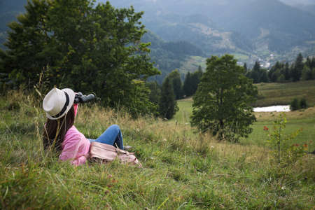 Young woman with binoculars enjoying mountain landscape. Space for textの写真素材