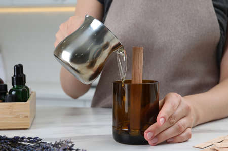 Woman making homemade candle at table in kitchen, closeup