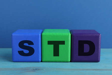 Abbreviation STD made with cubes on light blue wooden tableの写真素材