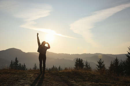 Silhouette of woman at sunrise in mountains, back view. Space for textの写真素材