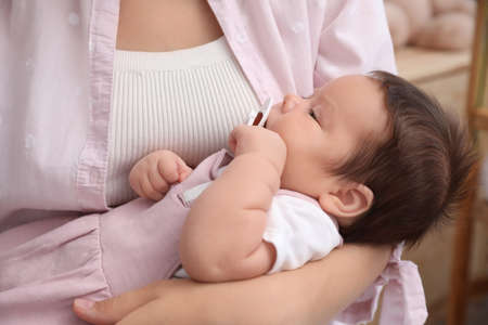 Mother holding her cute little baby with pacifier at home, closeupの写真素材