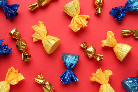 Many candies in colorful wrappers on red background, flat layの写真素材