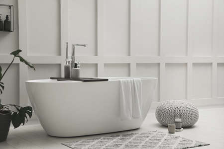 Modern ceramic bathtub and green plant near white wall indoorsの写真素材