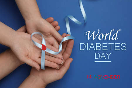 World Diabetes Day. People holding light blue ribbon with paper blood drop on color background, top viewの写真素材
