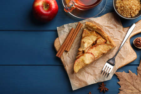 Flat lay composition with delicious apple pie, ingredients and tea on blue wooden table. Space for textの写真素材