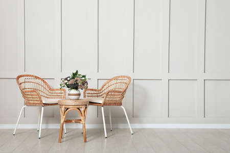 Simple room interior with set of wicker furniture, beautiful flowers and empty wall. Space for designの写真素材