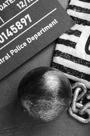 Metal ball with chain, prison uniform and mugshot letter board on gray table, flat layの写真素材