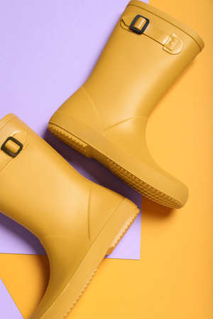 Pair of yellow rubber boots on color background, top viewの写真素材