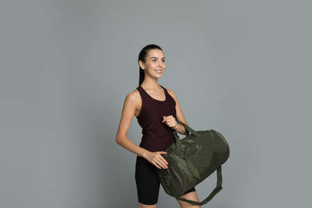 Beautiful woman with sports bag on gray backgroundの写真素材