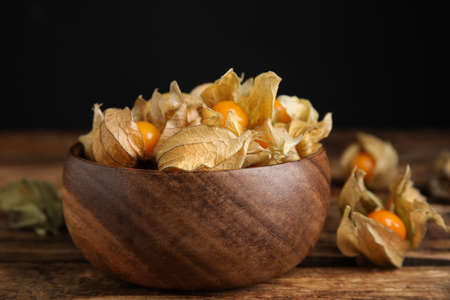 Ripe physalis fruits with dry husk on wooden table, closeupの写真素材