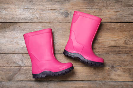 Pair of bright pink rubber boots on wooden background, top viewの写真素材