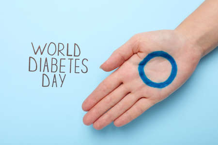 Woman showing palm with drawn blue circle near text World Diabetes Day on color background, top viewの写真素材