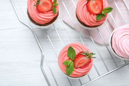 Delicious cupcakes with cream and strawberries on white wooden table, top viewの写真素材
