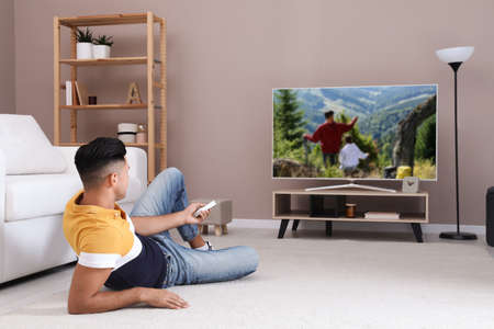 Man watching television at home. Living room interior with TV on standの写真素材