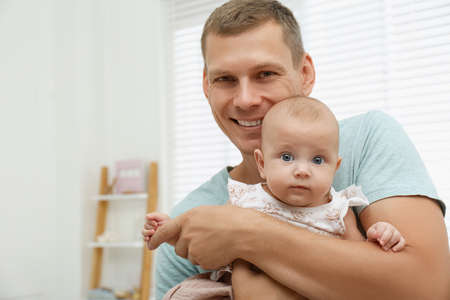 Happy father with his little baby at home. Space for text
