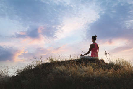 Woman meditating on hill near sea, back view. Space for textの写真素材
