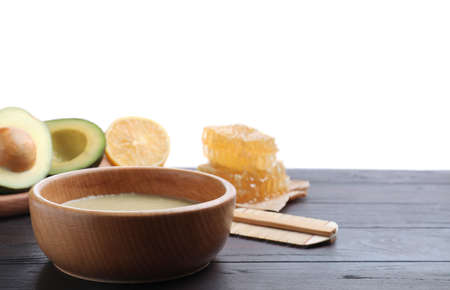 Homemade hair mask in bowl, fresh ingredients and bamboo comb on wooden table against white background. Space for textの写真素材