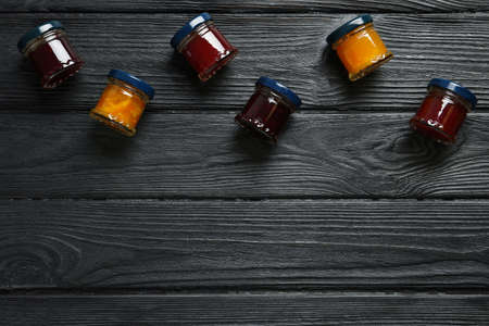 Jars of different jams on black wooden table, flat lay. Space for textの写真素材