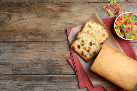 Delicious cake with candied fruits on wooden table, flat lay. Space for textの写真素材