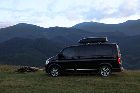Black van parked in clearing among mountainsの写真素材