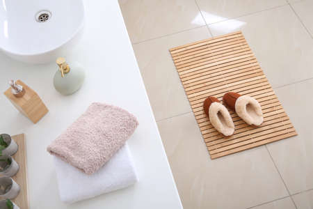 Wooden mat with slippers on floor in bathroomの写真素材