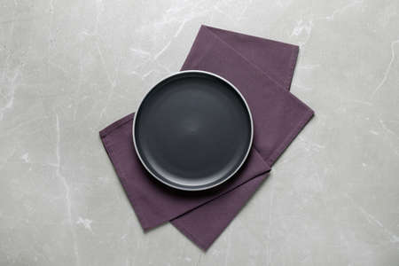 New dark plate and napkin on light gray table, top view