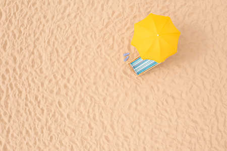 Yellow beach umbrella, sunbed and flip flops on sandy coast, aerial view. Space for textの写真素材