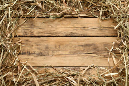 Frame made of dried hay on wooden background, top view. Space for textの写真素材