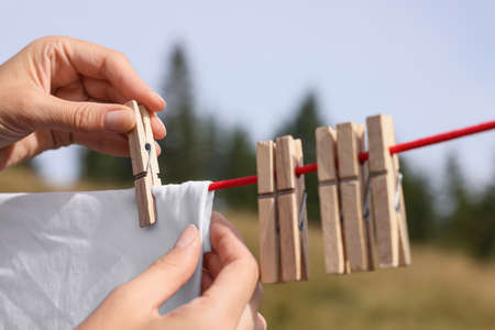 Woman hanging clean laundry with clothespins on washing line outdoors, closeupの写真素材