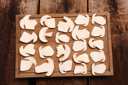 Board with slices of mushrooms on wooden table prepared for natural dehydration, top viewの写真素材