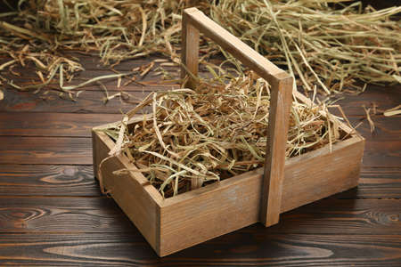 Dried hay in crate on wooden tableの写真素材