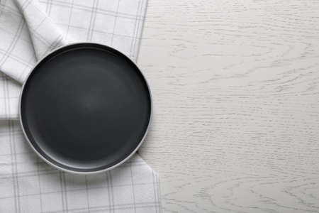 New dark plate and tablecloth on white wooden table, top view. Space for textの写真素材