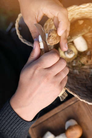 Man peeling mushroom with knife over basket, closeupの写真素材