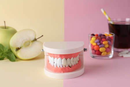 Model of jaw with teeth, healthy and harmful products on color backgroundの写真素材