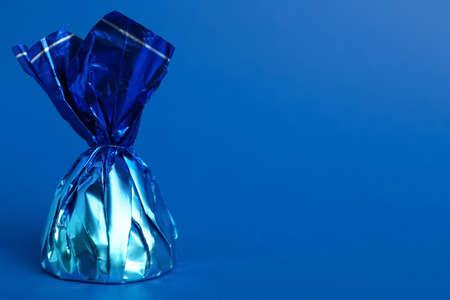 Candy in bright wrapper on blue background. Space for textの写真素材