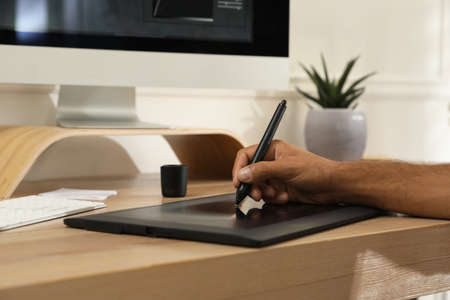 Professional retoucher working on graphic tablet at desk, closeup
