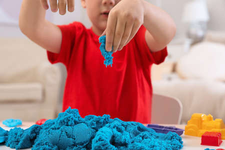 Little boy playing with bright kinetic sand at table indoors, closeupの写真素材