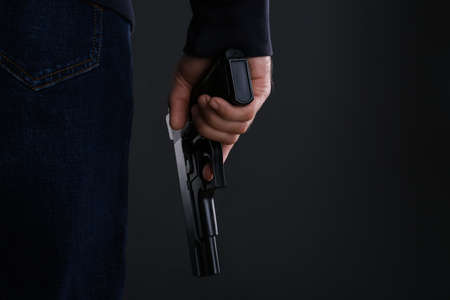 Man holding gun on black background, closeup