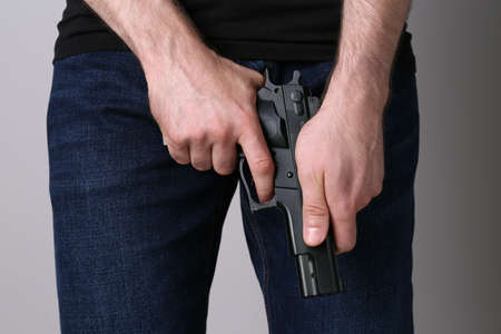 Man loading gun on gray background, closeup