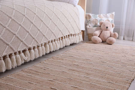 Stylish children's room interior with beige rug and bed