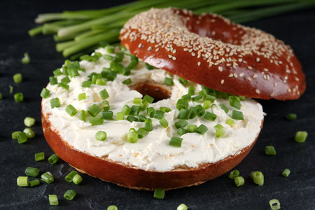 Delicious bagel with cream cheese and green onion on black table, closeupの写真素材