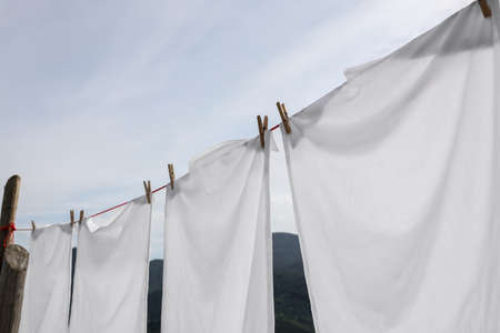 Washing line with clean laundry and clothespins outdoorsの写真素材