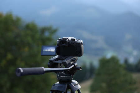 Taking photo of beautiful landscape with camera mounted on tripod outdoorsの写真素材