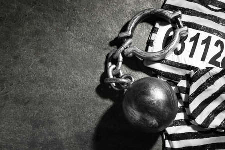 Prisoner ball with chain and jail clothes on gray table, flat lay. Space for textの写真素材