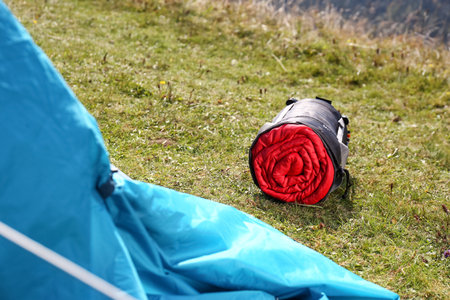 Red sleeping bag in sack on green grass outdoorsの写真素材
