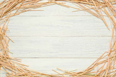 Frame made of dried hay on white wooden background, top view. Space for text