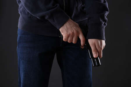 Man loading gun on black background, closeup