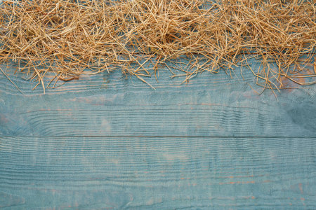 Heap of dried hay on light blue wooden background, flat lay. Space for textの写真素材