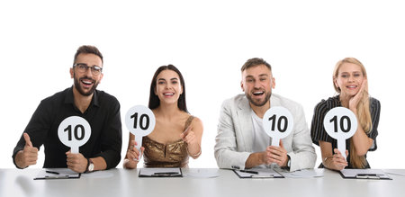 Panel of judges holding signs with highest score at table on white backgroundの写真素材