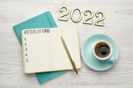 Making resolutions for 2022 new year. Flat lay composition with notebook on white wooden tableの写真素材